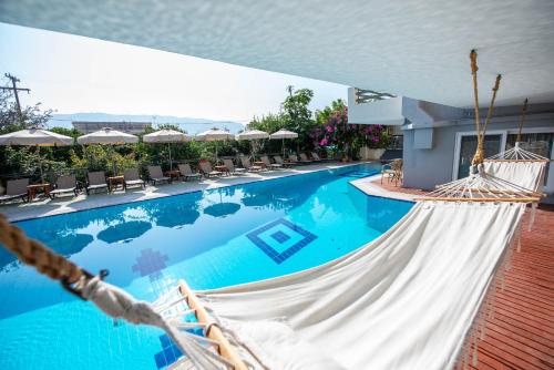 Blick auf einen Pool mit Stühlen und Sonnenschirmen in der Unterkunft Saga Hotel in Poros