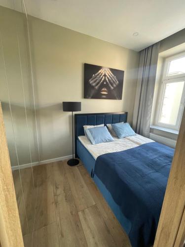 a bedroom with a blue bed and a window at Łódź4HOME Apartament in Łódź