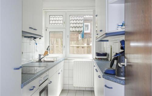 eine weiße Küche mit einem Waschbecken und einem Fenster in der Unterkunft Duinennest in Bergen aan Zee