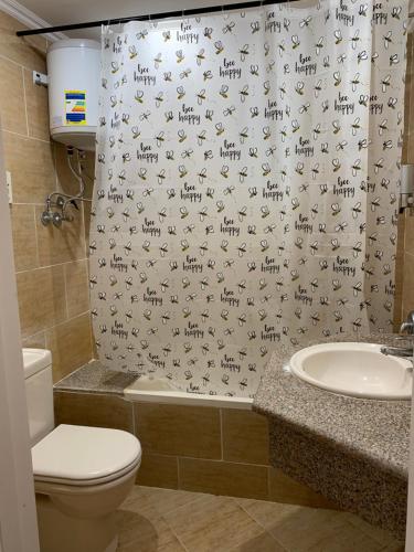 a bathroom with a shower curtain with a toilet and a sink at Sunset pearl Sahl Hashesh in Hurghada