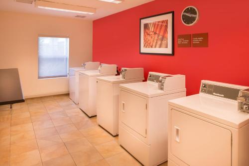 lavadero con lavadoras blancas y secadoras contra una pared roja en TownePlace Suites Thousand Oaks Ventura County, en Thousand Oaks