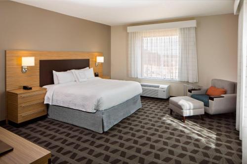 a hotel room with a bed and a chair at TownePlace Suites by Marriott Foley at OWA in Foley