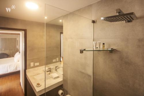 a bathroom with a shower and a sink and a bed at Las Mimosas by Wynwood House in Lima