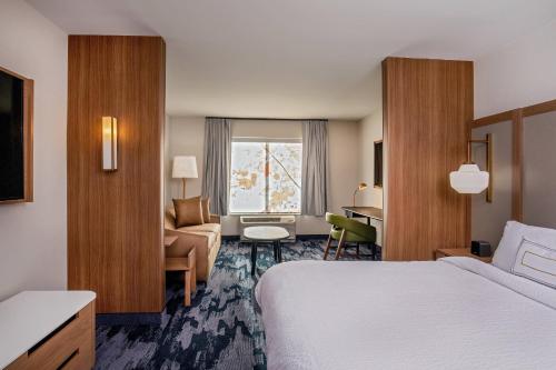 een hotelkamer met een bed, een stoel en een raam bij Fairfield Inn & Suites by Marriott Boston Walpole in Walpole