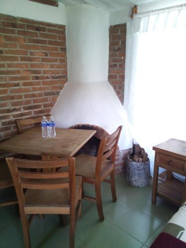 a table and chairs in a room with a brick wall at La Misión Cabañas Chignahuapan in Chignahuapan