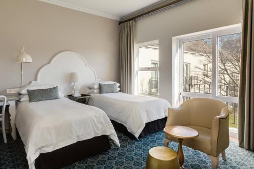 Cape Town的住宿－開普敦莫布雷帝王花萬豪酒店&度假村，一间卧室设有两张床、一把椅子和一个窗户。