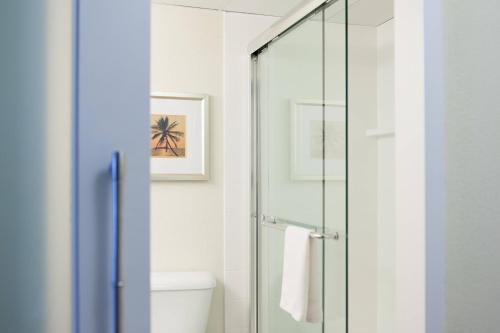 baño con cabina de ducha de cristal y aseo en West Palm Beach Marriott en West Palm Beach