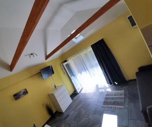 a living room with yellow walls and a large window at Csatang Vendégház in Siófok