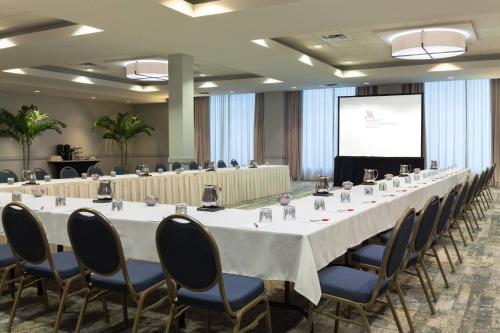 a conference room with a long table and chairs and a screen at Fort Lauderdale Marriott North in Fort Lauderdale