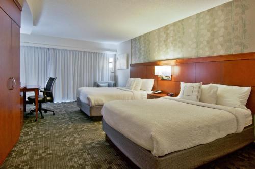 a hotel room with two beds and a desk at Courtyard by Marriott Clarksville in Clarksville