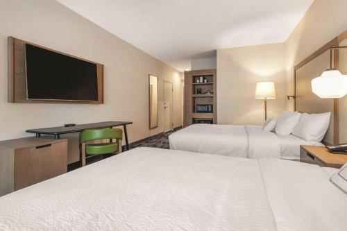 a hotel room with two beds and a desk and a tv at Fairfield Inn & Suites by Marriott Kansas City Shawnee in Shawnee