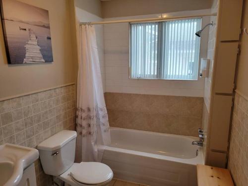 a bathroom with a toilet and a tub and a sink at Le petit chalet de pierres in Sainte-Luce-sur-Mer