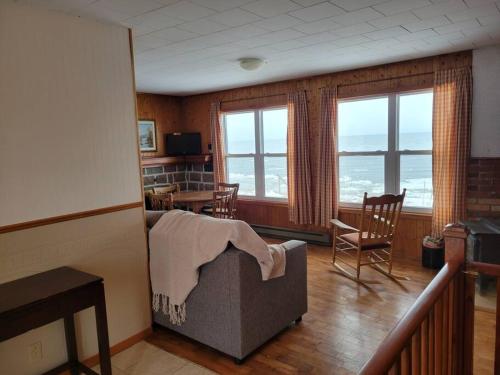 - un salon avec un lit, des chaises et des fenêtres dans l'établissement Le petit chalet de pierres, à Sainte-Luce-sur-Mer