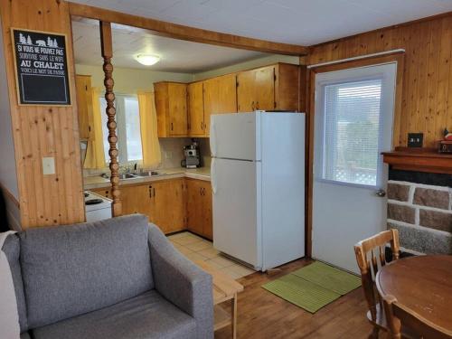une cuisine avec un réfrigérateur blanc et une table dans l'établissement Le petit chalet de pierres, à Sainte-Luce-sur-Mer