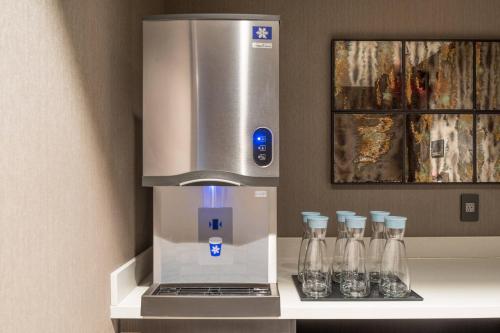 a coffee machine with four glass bottles on a shelf at AC Hotel by Marriott Boston Cleveland Circle in Boston