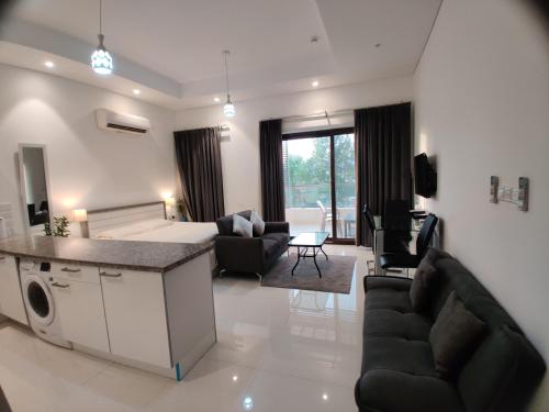 a living room with a kitchen and a living room with chairs at Hawana Salalah Laguna Studio in Salalah