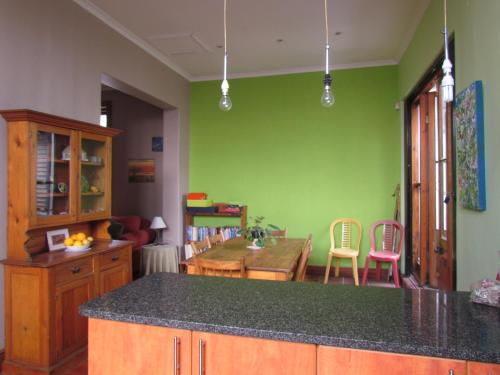 a kitchen with green walls and a table and chairs at Victorian Woodstock in Cape Town