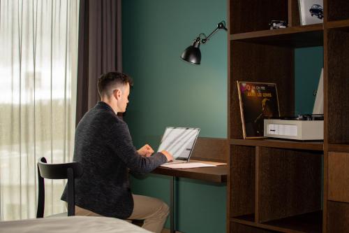 a man sitting at a desk with a laptop computer at Autohalle Hotel in Andelfingen