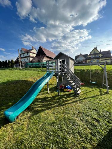 a playground with a blue slide in a field at Pokoje u Hani - sauna, balia z hydromasażem in Bukowina Tatrzańska