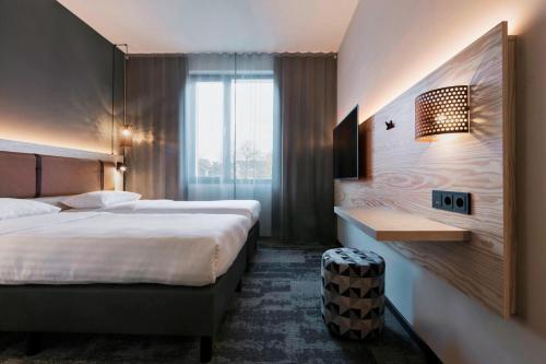 a hotel room with two beds and a desk at Moxy Darmstadt in Darmstadt