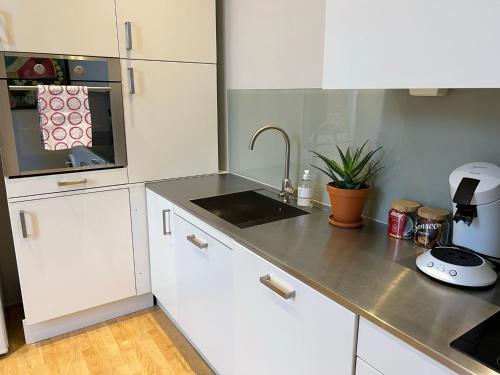 a kitchen with white cabinets and a sink at Fredrikstad Cicignon, peaceful but central with garden, parking and long stay facilities in Fredrikstad