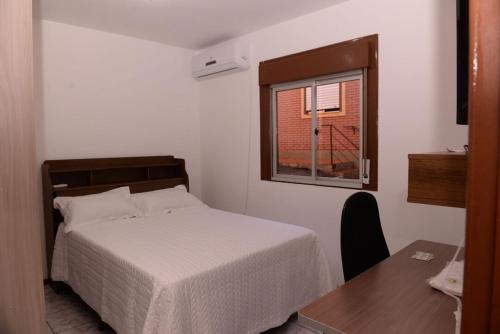 a bedroom with a bed and a table and a window at Apto completo e aconchegante em Santa Rosa RS in Santa Rosa