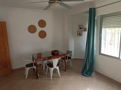 Una mesa de comedor con sillas y un ventilador de techo. en Apartamento Bajo en Valdelagrana, Primera Línea de Playa, en El Puerto de Santa María