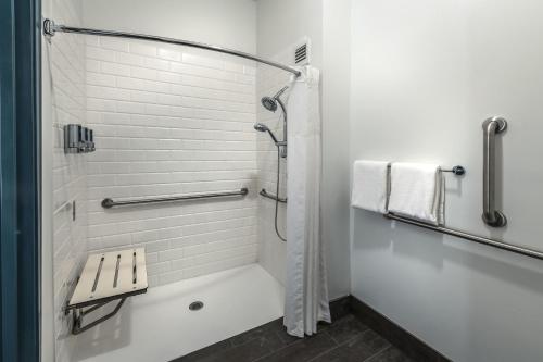 a white bathroom with a shower and a bench at Four Points by Sheraton Anchorage Downtown in Anchorage