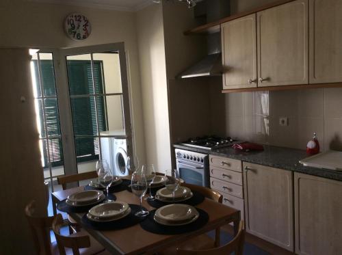 Una cocina con una mesa con platos y copas de vino. en Excelente T3 Duplex Funchal, en Funchal