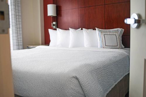 a bed with white sheets and pillows in a hotel room at Residence Inn Aberdeen at Ripken Stadium in Aberdeen