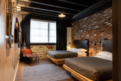 a bedroom with two beds and a brick wall at Moxy Nashville Downtown in Nashville