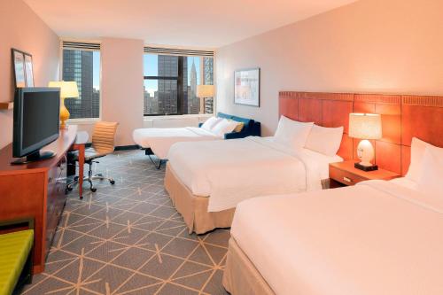 a hotel room with two beds and a flat screen tv at Courtyard New York Manhattan/Midtown East in New York