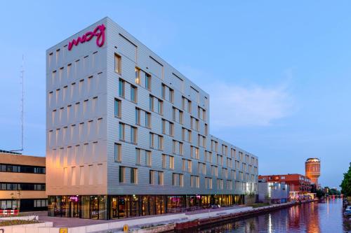 a white building with a sign on it next to a river at Moxy Utrecht in Utrecht