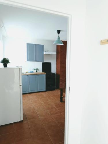 a kitchen with blue cabinets and a white refrigerator at Przystań Tło dla Mew in Rydzewo