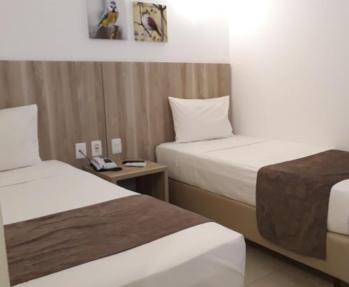 um quarto de hotel com duas camas e um telefone em Pena Branca Hotel e Eventos em Santo Antônio de Jesus