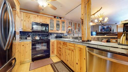 a kitchen with wooden cabinets and a black refrigerator at Aspen Creek #227 condo in Mammoth Lakes