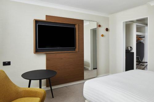 a hotel room with a bed and a television on a wall at Cardiff Marriott Hotel in Cardiff