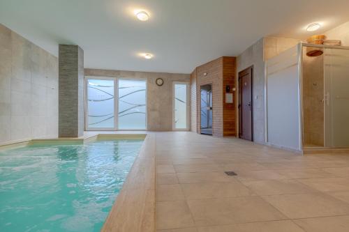an indoor swimming pool with blue water in a building at Casa Luxury Wellness Apartman By BLTN in Siófok