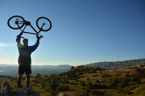 a man holding up a bike on top of a mountain at Apartman Sara in Pluzine