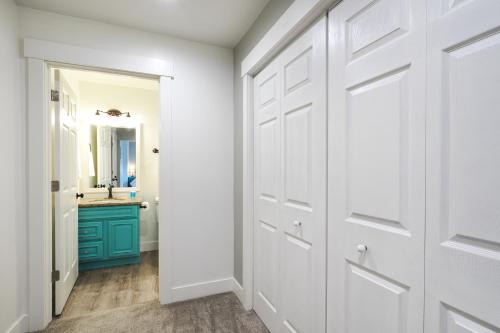 a hallway with white doors and a bathroom with a sink at Orem Vacation Rental Apartment Near BYU Campus! in Orem