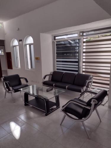 uma sala de estar com um sofá preto e cadeiras em Las Margaritas Casa de Huéspedes em Cancún