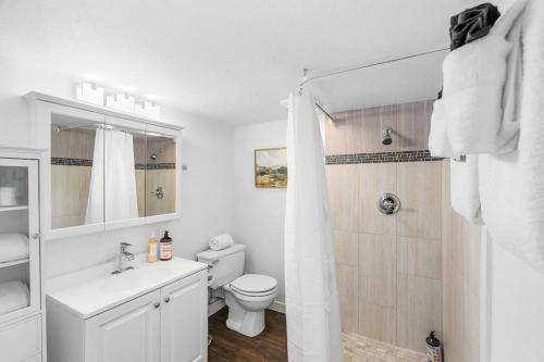 a white bathroom with a toilet and a shower at Lilac In Law, Picturesque lower unit in Seattle