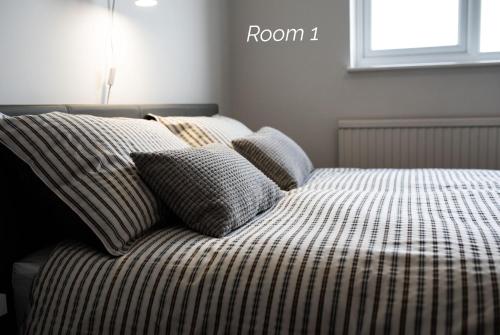 a bed with striped sheets and pillows in a bedroom at Town House Chantry - With Self Check In and Free Parking - Rooms at ipswichdigs in Ipswich