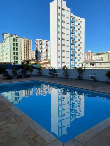 a swimming pool in front of some tall buildings at Hotel Lux in Poços de Caldas
