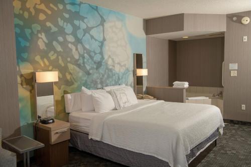 エリーにあるCourtyard by Marriott Erie Ambassador Conference Centerのベッド付きの客室で、壁には絵画が飾られています。