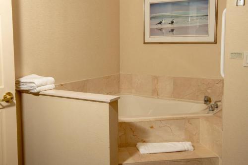 a bathroom with a tub and a sink with towels at Courtyard by Marriott Erie Ambassador Conference Center in Erie