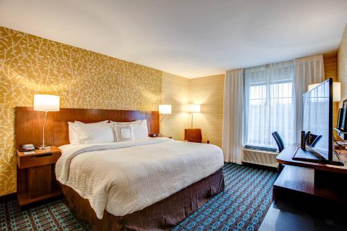 Fairfield Inn & Suites by Marriott Springfield Holyoke في هوليوك: غرفة فندقية بسرير وتلفزيون بشاشة مسطحة