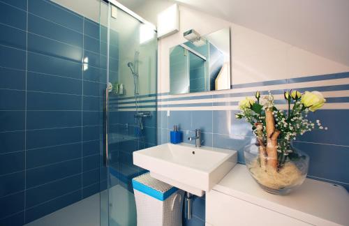 a blue bathroom with a sink and a vase of flowers at De luxe Apartment GOLOB Kranjska Gora in Kranjska Gora