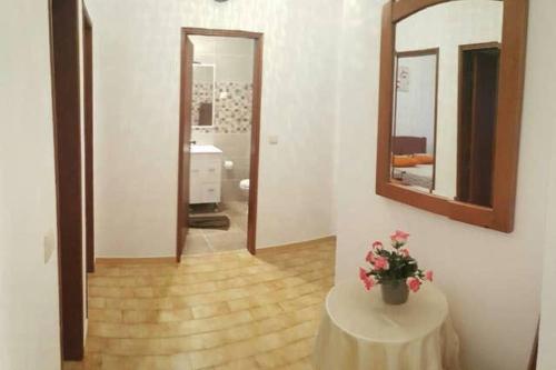 Una habitación con una mesa con un jarrón de flores. en Chez Rosa, en Vila Real de Santo António