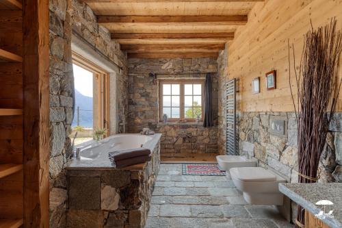 Baño de piedra con 2 lavabos y bañera en Villa Cassia, en Stazzona